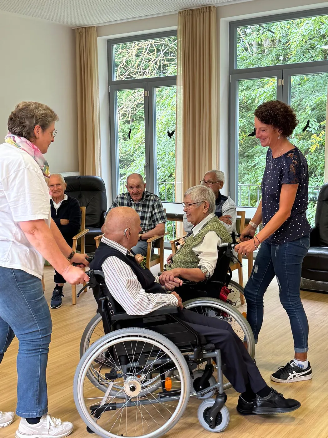 Tanz im Rollstuhl: zwei Gäste reichen sich die Hände, begleitet vom Team